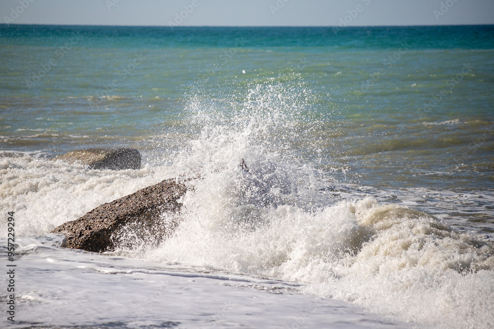 A sea wave breaks against the rocks, water splashes in the sky. Tidal wave. A sea wave breaks against the rocks, water splashes in the sky. Tidal wave.