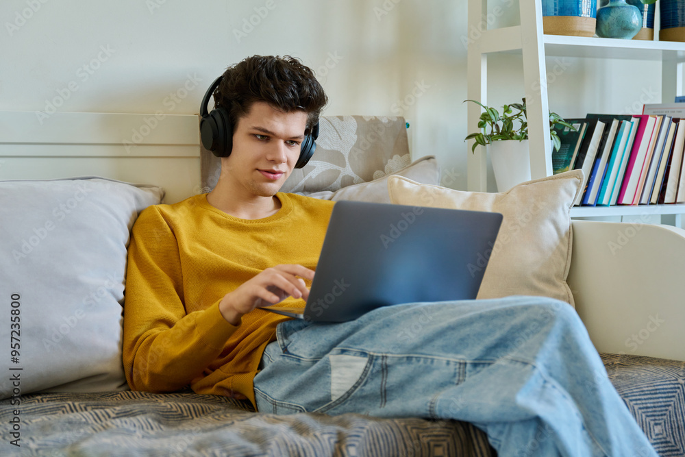 Young guy 19-20 years old in headphones using laptop, talking on video call Young guy 19-20 years old in headphones using laptop, talking on video call