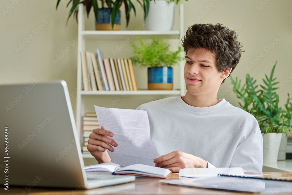 Smiling happy young guy reading letter, paper document Smiling happy young guy reading letter, paper document