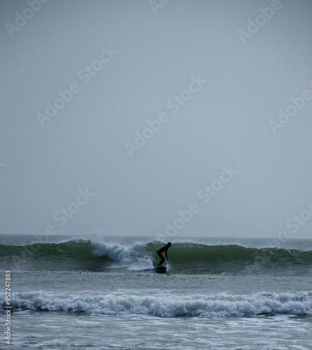 Dynamic silhouette of a surfer catching a wave during golden hour.