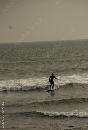 Dynamic silhouette of a surfer catching a wave during golden hour.
