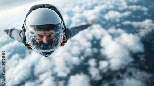 A skydiver is captured in mid-air, diving confidently with arms spread out, surrounded by the majestic backdrop of fluffy clouds during a high-altitude jump. photo