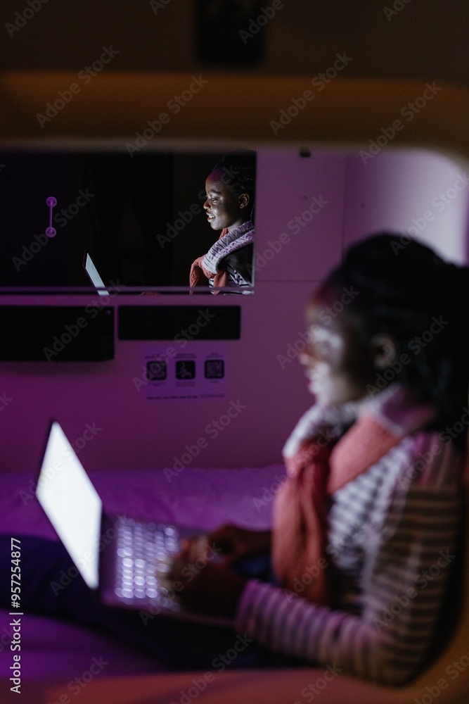 Mirror reflection of woman watching laptop in room of capsule hotel Mirror reflection of woman watching laptop in room of capsule hotel