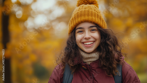 Portrait of young happy smiling hispanic girl in autumn park, positive cheerful young woman enjoying a walk outdoors in autumn forest. Active lifestyle, good health. Enjoying outdoors.