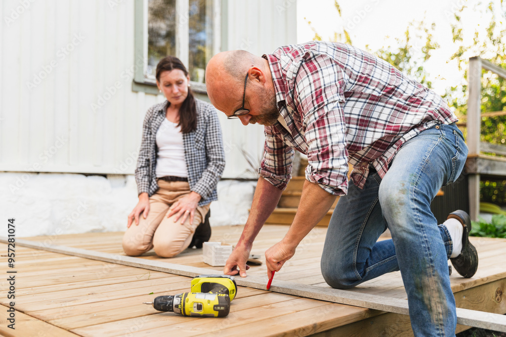 Handyman Fixing Wooden Floor with Drill in Their Backyard Handyman Fixing Wooden Floor with Drill in Their Backyard