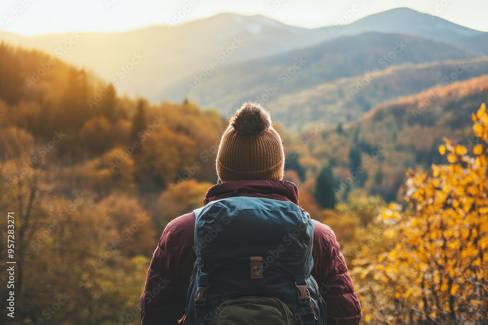 Back view of unrecognizable solitary hiker admires the view of the mountain during autumn, with warm light. Back view of unrecognizable solitary hiker admires the view of the mountain during autumn, with warm light.