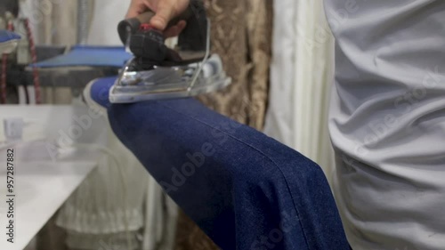 A dry cleaner irons jeans