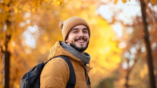 Portrait of young happy smiling caucasian man in autumn park, positive cheerful young man enjoying a walk outdoors in autumn forest. Active lifestyle, good health. Enjoying outdoors.