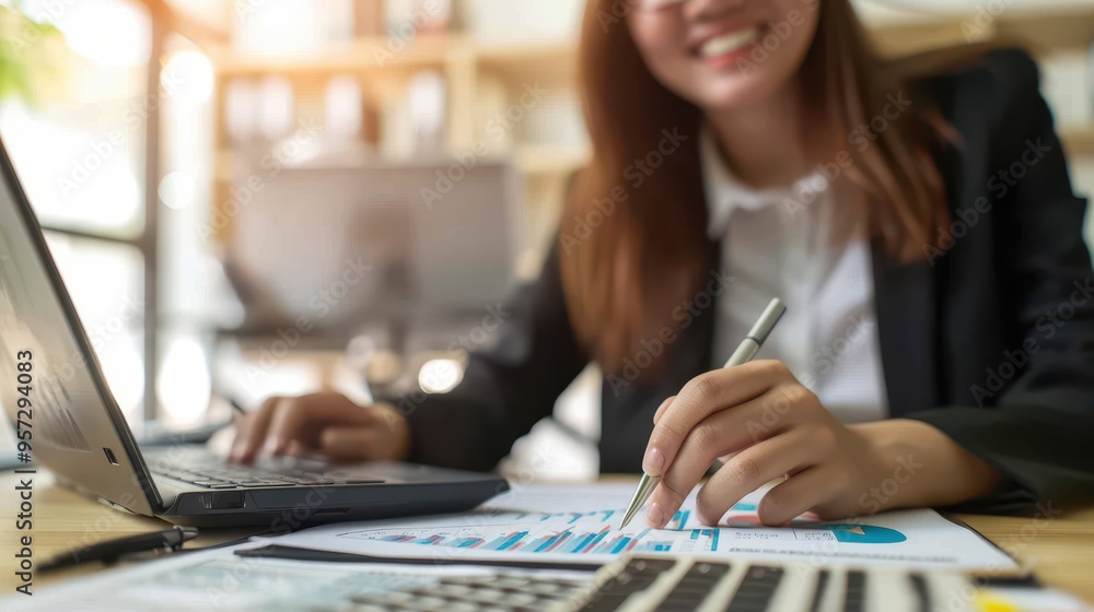 Businesswoman Analyzing Financial Data on Laptop and Paper Charts in Modern Office Setting Businesswoman Analyzing Financial Data on Laptop and Paper Charts in Modern Office Setting