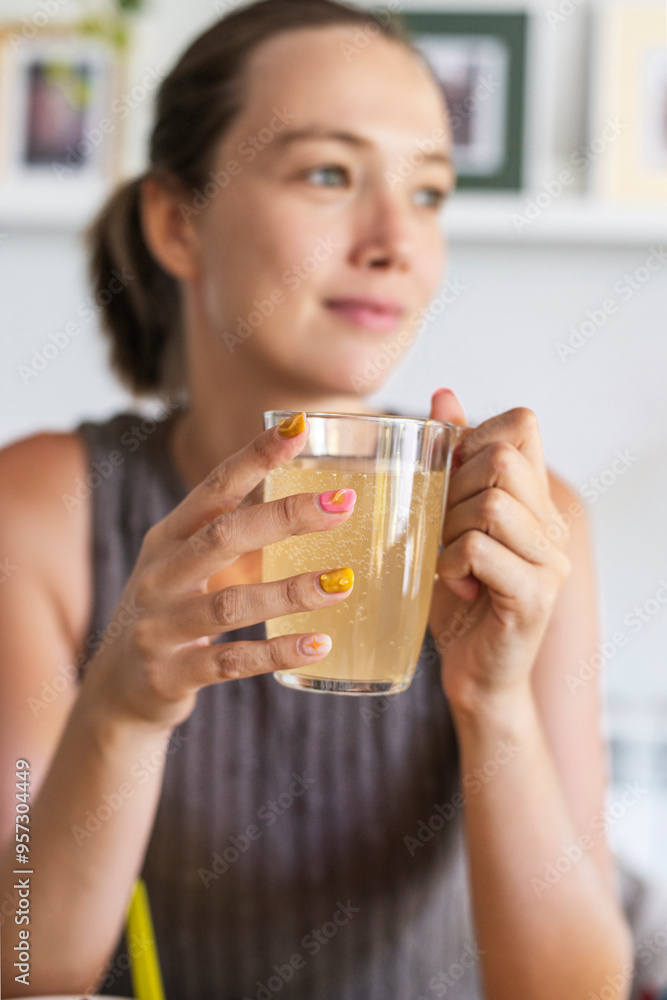 Thoughtful woman holding glass of kombucha, healthy lifestyle Thoughtful woman holding glass of kombucha, healthy lifestyle