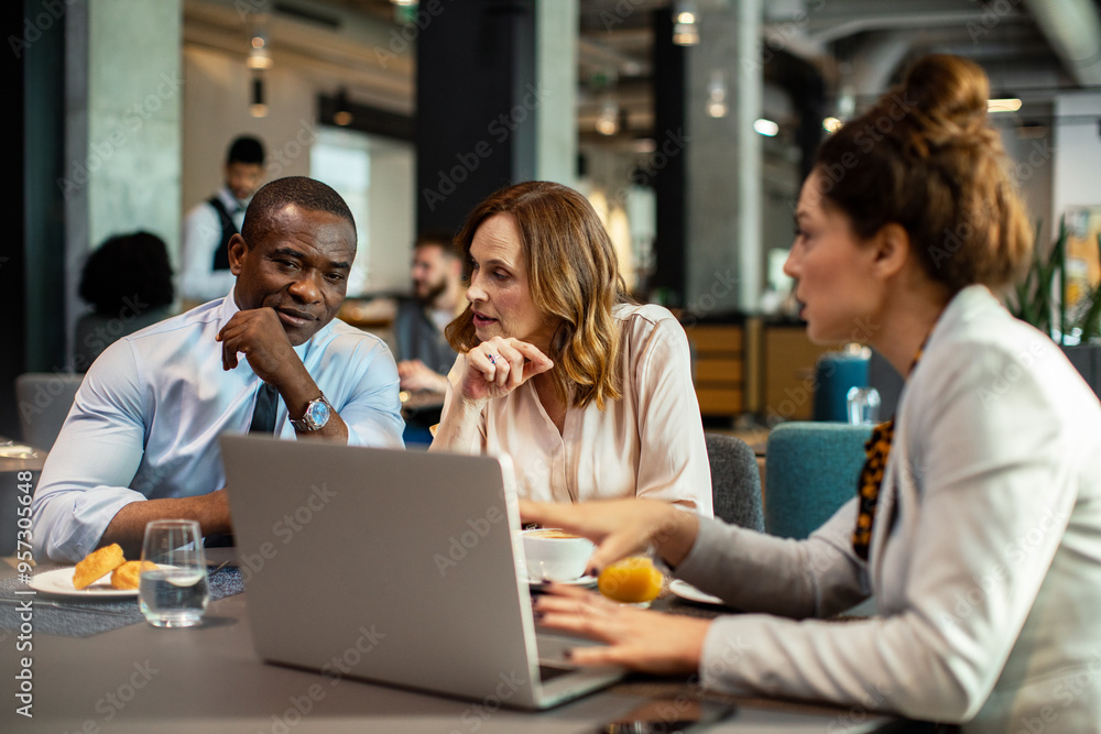 Business team discussing work over a laptop in a hotel restaurant Business team discussing work over a laptop in a hotel restaurant