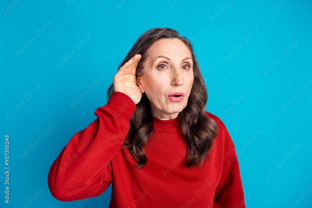 Photo of pretty aged lady arm ear eavesdrop wear red pullover isolated on blue color background Photo of pretty aged lady arm ear eavesdrop wear red pullover isolated on blue color background
