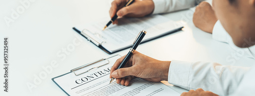 Business executive signing contract agreement document on the bale with the help from company attorney or lawyer service in law firm office. Business investing and finalizing legal processing. Shrewd