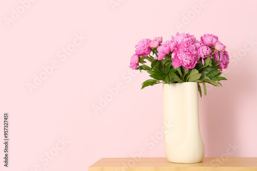 Vase of pink peonies on shelving unit near color wall