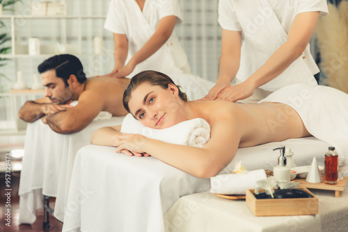 Caucasian couple customer enjoying relaxing anti-stress spa massage and pampering with beauty skin recreation leisure in day light ambient salon spa at luxury resort or hotel. Quiescent