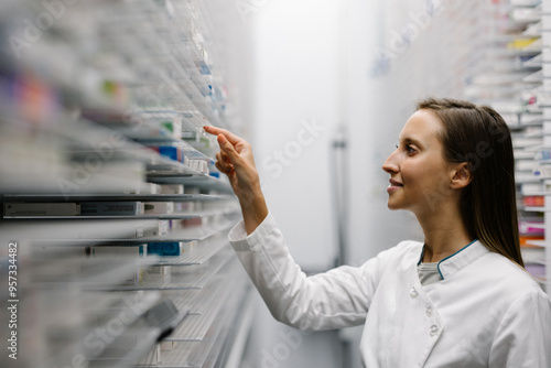 Pharmacist organizing medicine on shelf in modern pharmacy