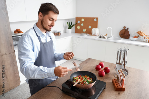 Young man spicing fried veg...