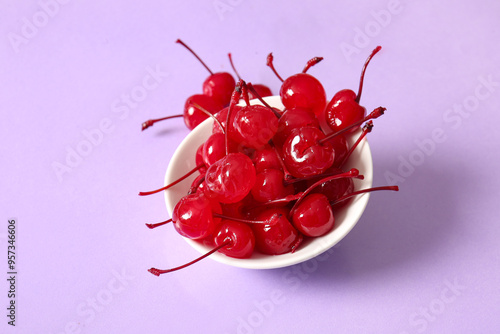 Fotografie Bowl of tasty maraschino cherries on lilac background