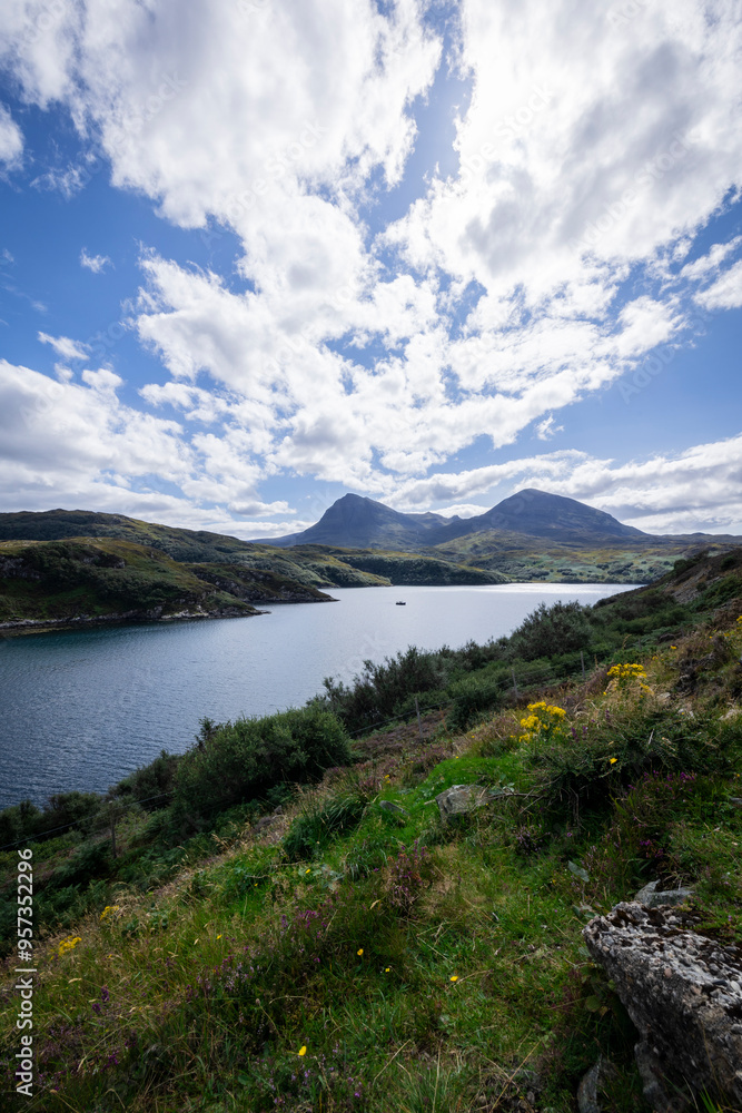 The image shows a body of water surrounded by hills in Loch a' Chàirn Bhàin, Scotland. The scene includes clouds, nature, water, sky, mountains, and a highland landscape. The image shows a body of water surrounded by hills in Loch a' Chàirn Bhàin, Scotland. The scene includes clouds, nature, water, sky, mountains, and a highland landscape.