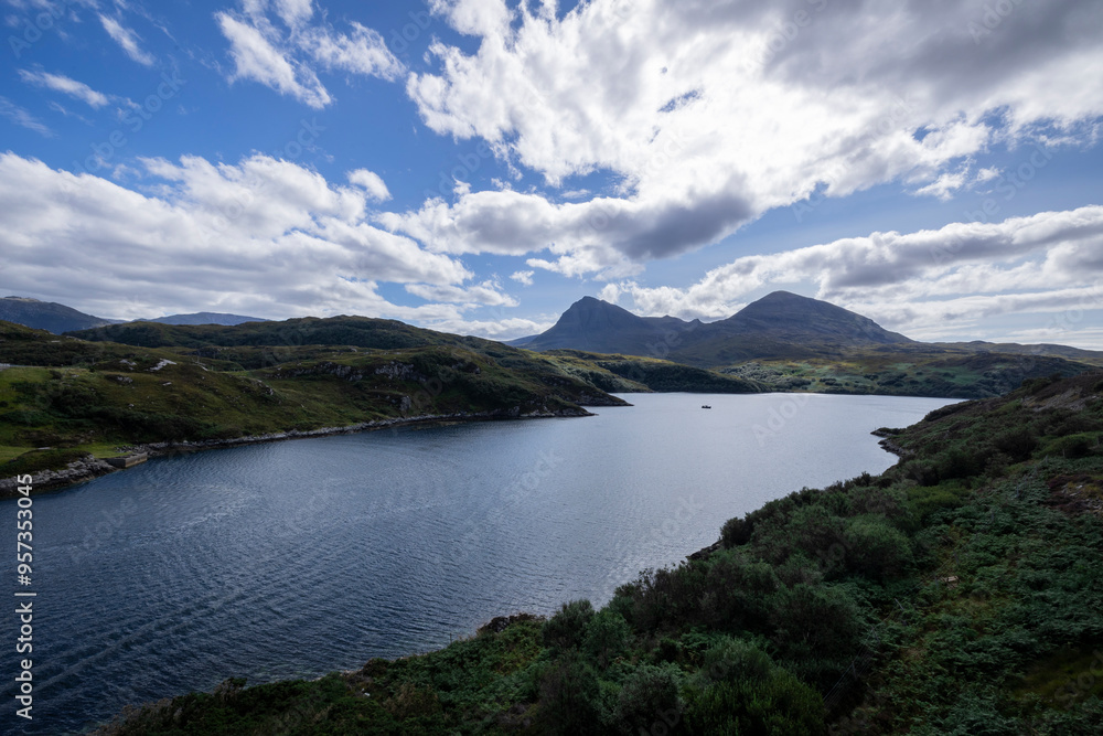 The image shows a body of water surrounded by hills in Loch a' Chàirn Bhàin, Scotland. The scene includes clouds, nature, water, sky, mountains, and a highland landscape. The image shows a body of water surrounded by hills in Loch a' Chàirn Bhàin, Scotland. The scene includes clouds, nature, water, sky, mountains, and a highland landscape.