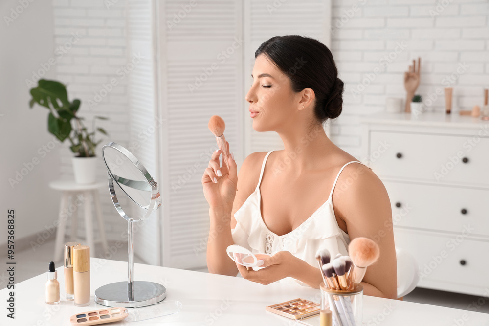 Beautiful young woman with makeup brush and blush at table in salon Beautiful young woman with makeup brush and blush at table in salon