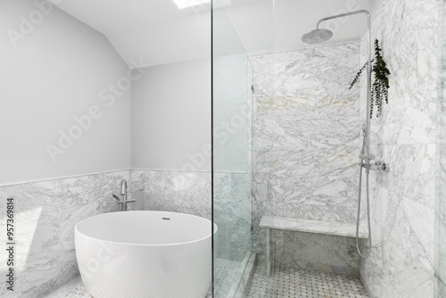Fotografia A bathroom with a shower with marble tiles and eucalyptus hanging from the chrome showerhead
