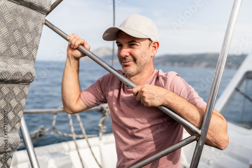 Sailor man holding metal bar on sailboat looking away photo