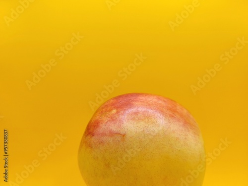 One colorful nectarine on a yellow backgorund.