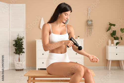 Young woman using percussive massage device at home