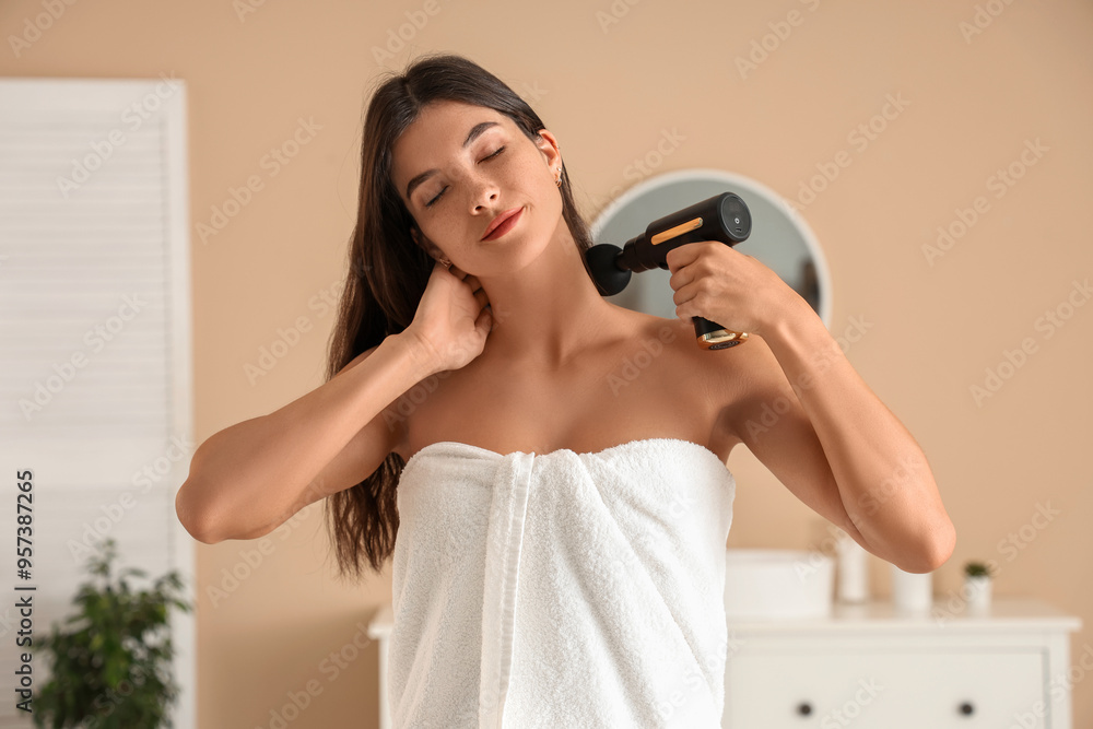 Young woman using percussive massage device at home Young woman using percussive massage device at home