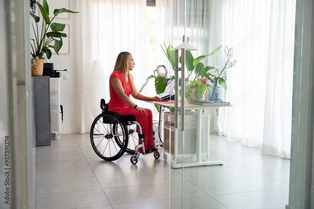 Person in wheelchair working at desk in home office Person in wheelchair working at desk in home office