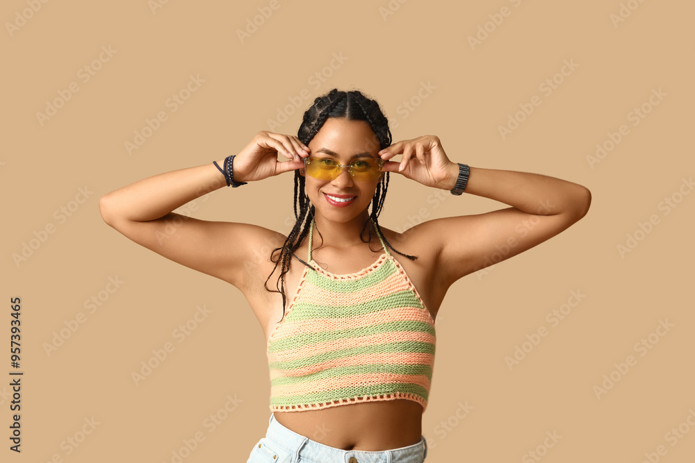 Beautiful young African-American woman in sunglasses with dreadlocks on brown background Beautiful young African-American woman in sunglasses with dreadlocks on brown background