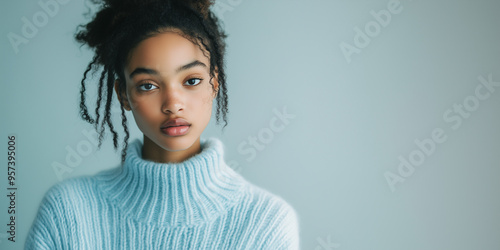 Black woman wearing a blue sweater and posing in studio