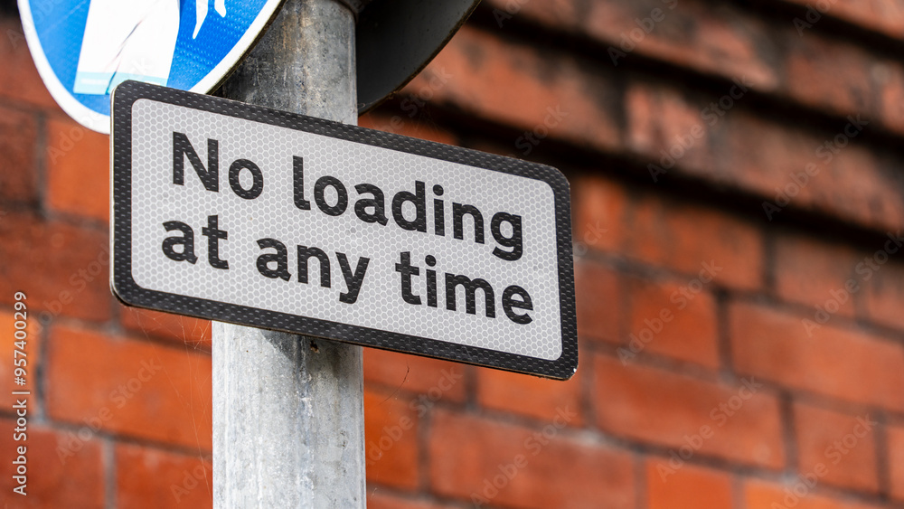 Close-up of a 'No Loading at Any Time' Sign on a Metal Pole Against a Brick Wall Close-up of a 'No Loading at Any Time' Sign on a Metal Pole Against a Brick Wall