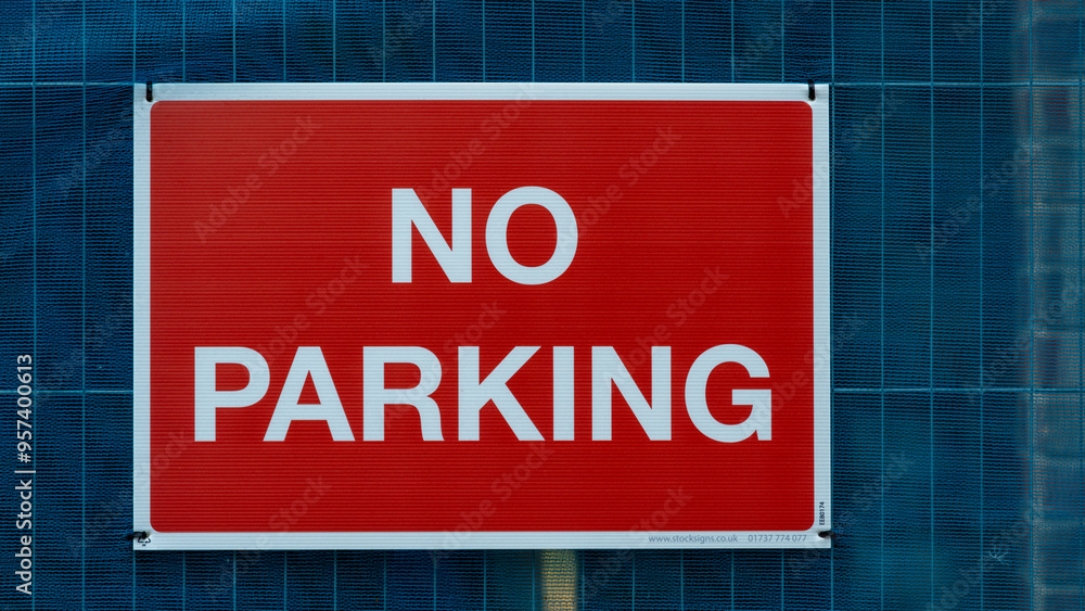 Red 'No Parking' Sign Against a Blue Fenced Background