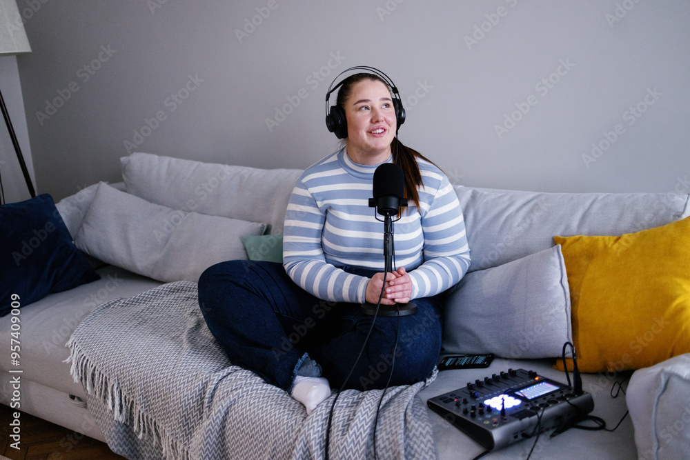Plus size woman recording podcast sitting cross-legged on sofa Plus size woman recording podcast sitting cross-legged on sofa