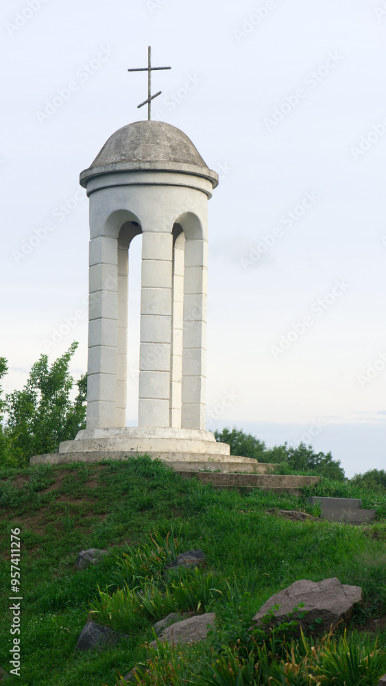 Fototapeta premium beautiful landscape and a small bell tower. a detail of the building a small bell tower with a cross stands on a hill. faith, religion. space for text. Christianity or Catholicism. autumn time
