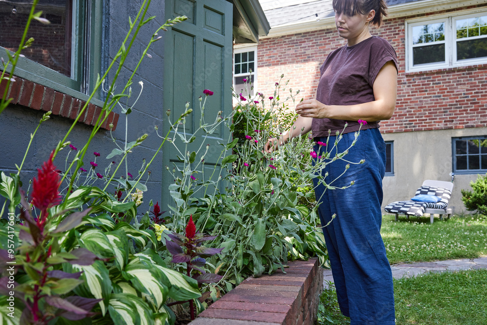 Woman is taking care of her flowers outside Woman is taking care of her flowers outside
