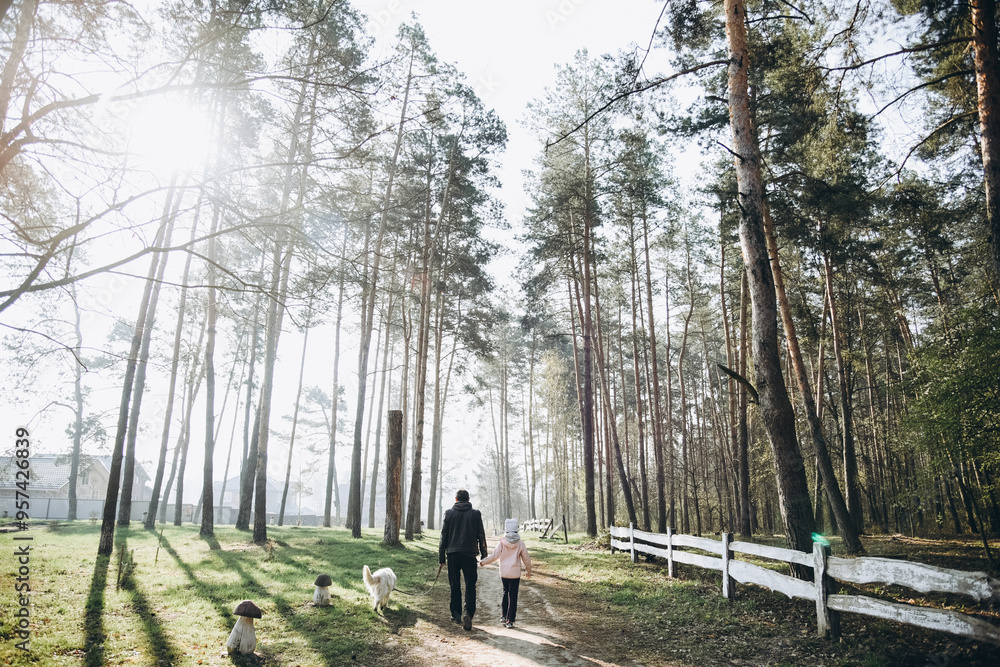 father and daughter are walking in the forest with a dog father and daughter are walking in the forest with a dog