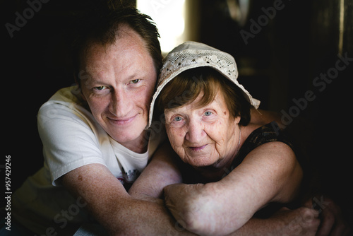 A warm and cozy home portrait of a man hugging his grandmother.