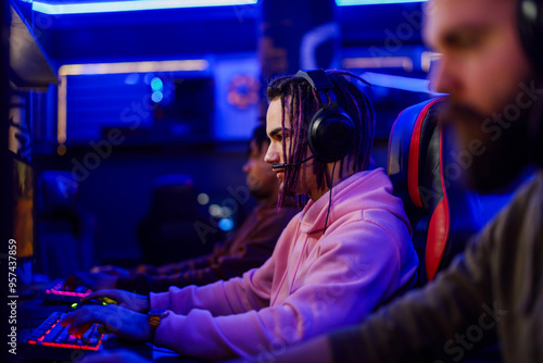 Focused gamer with headset and dreadlocks playing rts games in cybercafe photo