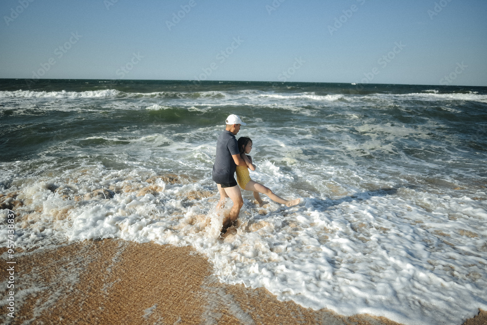 father and daughter jump on the waves father and daughter jump on the waves