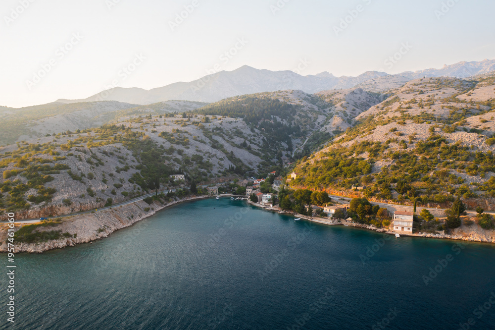 Fototapeta premium Coastal landscape at sunset overlooking a tranquil bay with mountains in the distance. 