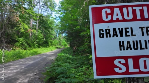 Caution Slow Gravel Trucks Hauling sign on the tree at Crown Land road of Ontario Province in Canada, North America. Gravel mining development for concrete, roads and construction. photo