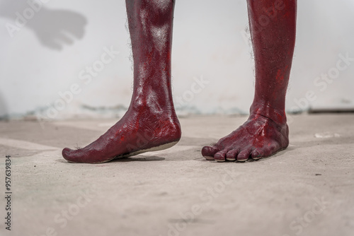 Dirty and horrifying red zombie feet displayed on white studio background. The gruesome Halloween-themed image emphasizes fear and shock, capturing the grotesque and unsettling nature of the undead. photo