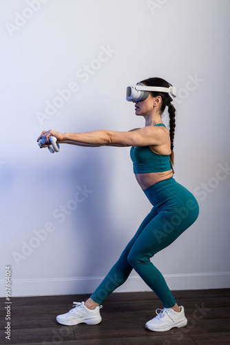 Woman wearing VR headset and exercising with dumbbells at home photo