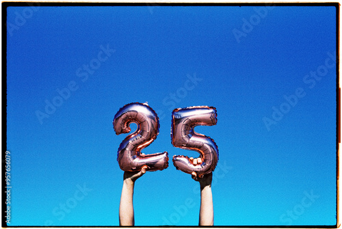 holding number-shaped balloons forming the number 25, 35mm photo