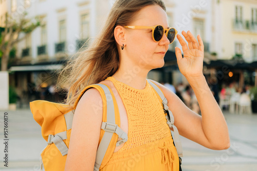 Woman with backpack ajusting sunglasses while walking in the cit photo