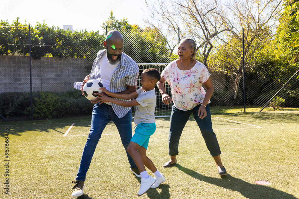 Obraz premium Playing soccer in backyard, grandparents and grandson enjoying outdoor time together