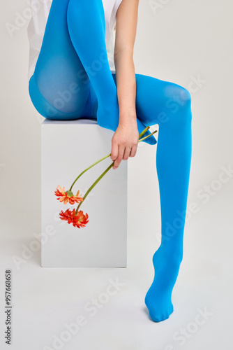 woman in blue stockings holding red flowers